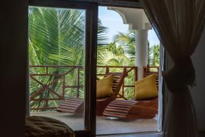 a room with a balcony with a view of a palm tree at Nungwi Garden Boutique Hotel in Nungwi