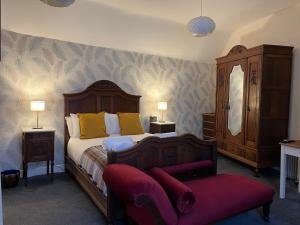 a bedroom with a large bed with a red bench at Painters at the Angel in Sudbury