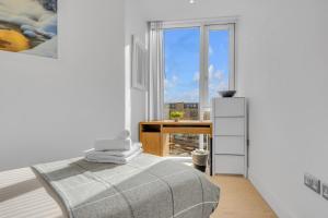 a bedroom with a bed and a desk and a window at Two Bedroom Serviced Apartment in Stratford in London