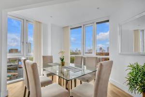 a dining room with a glass table and chairs and windows at Two Bedroom Serviced Apartment in Stratford in London