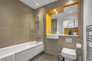 a bathroom with a toilet and a tub and a sink at Two Bedroom Serviced Apartment in Stratford in London
