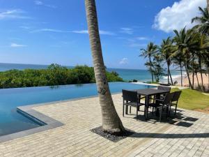 a table and chairs next to a palm tree next to a pool at Ocean Cottage in Kalametiya