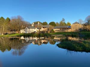 dom odbija się w wodzie jeziora w obiekcie Little Barn, Greendale Farm w mieście Barnstaple