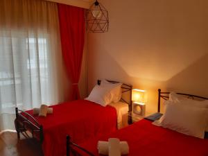 1 dormitorio con 2 camas con sábanas rojas y ventana en Elegante apartamento centrale, en Tríkala