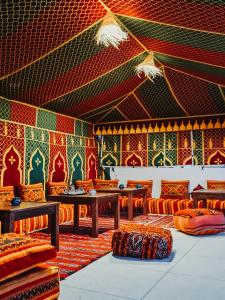 cactus surf house في Tamraght Ouzdar: غرفة بها طاولات وكراسي وجدار ملون