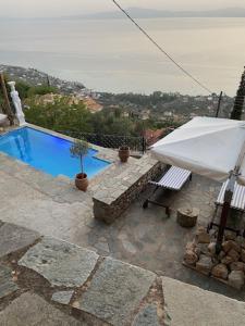 a swimming pool with a white umbrella and a bench at The Villa of Blues in Kalamata