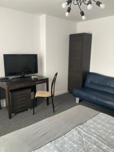 uma sala de estar com um sofá e uma secretária com uma televisão em Apartament Szaława em Kalisz