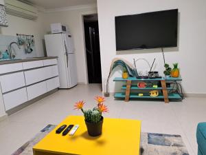 ein Wohnzimmer mit einem gelben Tisch und einem TV in der Unterkunft Pura vida in Aschkelon