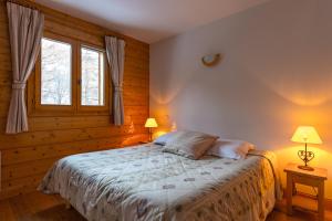 a bedroom with a bed with two lamps and two windows at Lagrange Vacances Le Hameau du Rocher Blanc in Saint-Chaffrey +15 photos