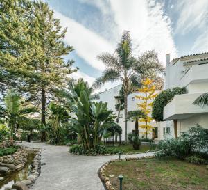 a courtyard with palm trees and a building at Puente Romano Beach Suites - private apartaments in Marbella