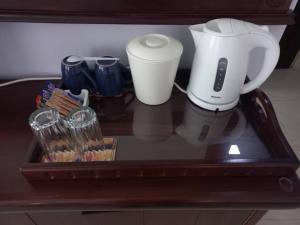 a counter with a coffee maker and cups on it at Crescent Lodge in Livingstone
