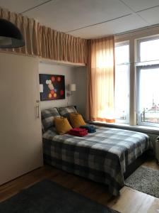 ein Schlafzimmer mit einem Bett mit gelben Kissen und einem Fenster in der Unterkunft Six in Amsterdam