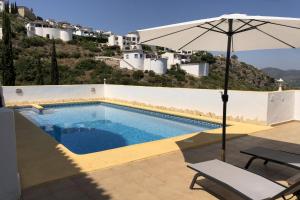 een zwembad met een parasol, een stoel en een tafel bij Villa Ventura 8 Pers in Pego