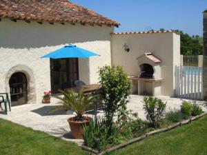 un patio avec une table avec un parasol et un four à pizza dans l'établissement Limerac Cottage, à Salles-Lavalette