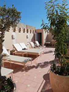 - une terrasse avec un bouquet de chaises longues et des arbres dans l'établissement DAR MAR'OUKA , Maison d'hôtes, à Marrakech