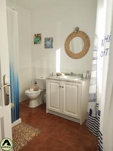 łazienka z toaletą, umywalką i lustrem w obiekcie VolKKanrentals SunBeam House w mieście Famara +26 zdjęć