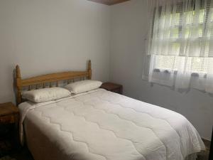 a bedroom with a white bed with a window at Cantinho do Sussego 2 in Campos do Jordão