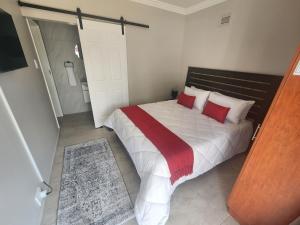 a bedroom with a large white bed with red pillows at Gateway@134 Guesthouse in Vryheid