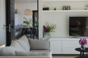 a living room with a white couch and a tv at Villa Dimi private pool, sea view & 3 bedrooms in Paleros