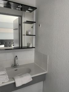 La salle de bains blanche est pourvue d'un lavabo et d'un miroir. dans l'établissement Fasthotel Mont de Marsan, à Mont-de-Marsan