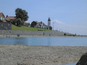 a body of water with a lighthouse in the background at Vakantiepark 't Urkerbos - 5 persoons Brabantse blokhut in Urk
