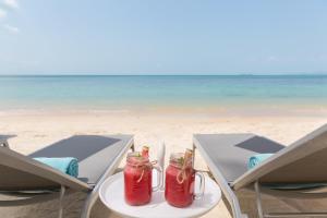 a table on the beach with two drinks on it at Sea&Sky Beach Resort in Mae Nam