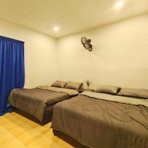 two beds in a room with a fan on the wall at A’Famosa Resort Pool Villa KTV Wifi BBQ Moments Villa in Kampong Alor Gajah