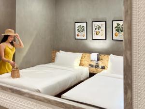 a woman standing between two beds in a hotel room at Hotel Dumaguete in Dumaguete