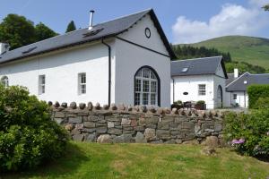 a white church with a stone wall in front of a building at Home Farm Cottages, Glendaruel, Argyll. Scotland in Clachan of Glendaruel