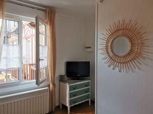 a room with a television and a mirror and a window at Studio chic, hyper centre, 4 minutes de la plage in Cabourg