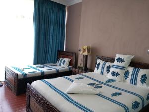 a bedroom with two beds with blue and white pillows at Blue Nile Guest House in Lalībela