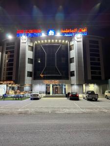 a parking lot in front of a building at night at AFAQ AL BATINAH - SAHAM in Şaḩam