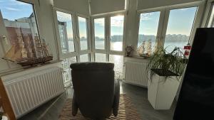 Zimmer mit großen Fenstern und einem Stuhl in einem Zimmer mit Aussicht in der Unterkunft Ferienwohnung mit Blick aufs Meer in Wilhelmshaven in Wilhelmshaven