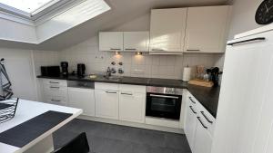 a kitchen with white cabinets and a black counter top at Ferienwohnung mit Blick aufs Meer in Wilhelmshaven in Wilhelmshaven +5 photos