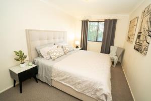 a bedroom with a large white bed and a window at Bushland Retreat in Gold Coast