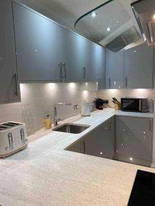 uma cozinha com armários azuis, um lavatório e um micro-ondas em Luxury Town centre apartment walking distance to RSC theatre em Stratford-upon-Avon