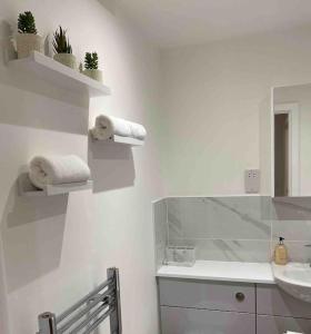 a bathroom with a sink and a mirror and towels at Luxury Town centre apartment walking distance to RSC theatre in Stratford-upon-Avon