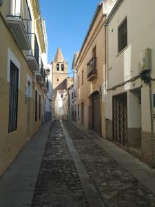 an empty alley with a church in the distance at Apartamentos de la Parte Antigua de Cáceres in Cáceres