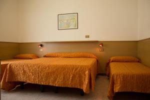 - une chambre d'hôtel avec 2 lits et des couvertures orange dans l'établissement Hotel Kennedy, à Caorle