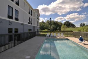 une piscine avec des chaises et un bâtiment dans l'établissement Super 8 by Wyndham Crossville TN, à Crossville