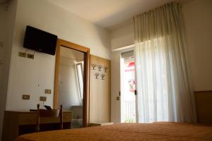a bedroom with a bed and a mirror and a window at Hotel Kennedy in Caorle