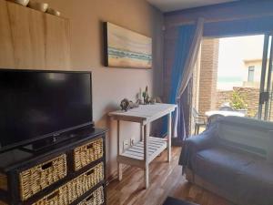 sala de estar con TV de pantalla plana y sofá en Beachfront Selfcatering, en Henties Bay