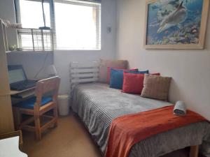 a bedroom with a bed and a desk and a window at Beachfront Selfcatering in Hentiesbaai