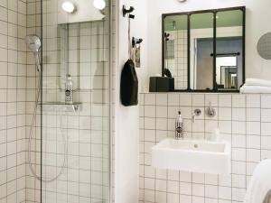 a white tiled bathroom with a sink and a shower at ibis Styles Amiens Centre in Amiens