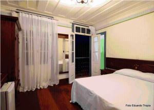 1 dormitorio con cama blanca y ventana en Pousada Laços de Minas, en Ouro Preto