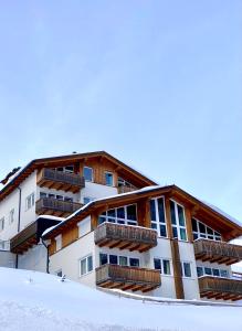 un bâtiment avec balcon dans la neige dans l'établissement Appartements "ALPS" by Kamper, à Obertauern