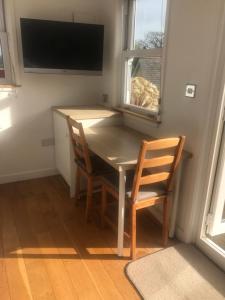 a dining room table with two chairs and a television at The Retreat in Charmouth