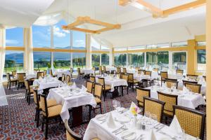 restauracja z białymi stołami, krzesłami i oknami w obiekcie Castlerosse Park Resort Holiday Homes w Killarney