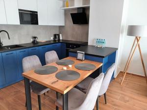 een keuken met een houten tafel en blauwe kasten bij Kima Apartament Bażantów 44 in Katowice
