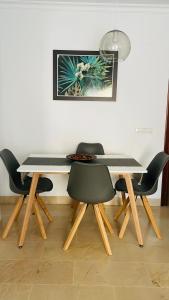 a dining room table with four chairs and a picture on the wall at Apartamento Málaga Centro in Málaga